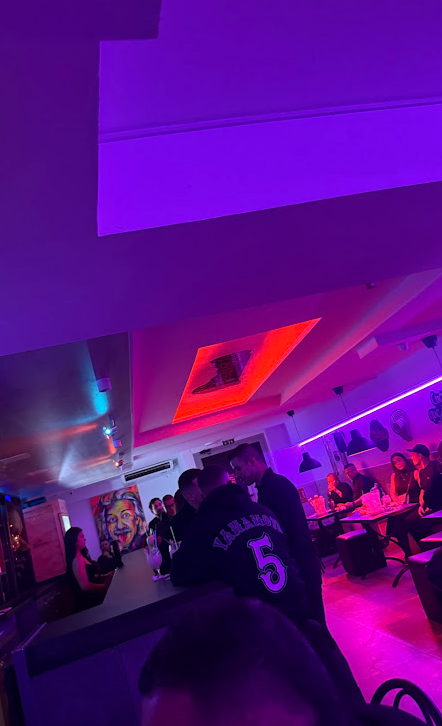 El interior de Tu Candela de noche, con luces moradas y gente en las mesas